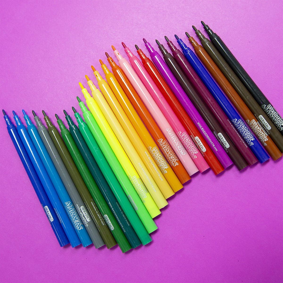 24 uncapped markers in assorted colors arranged diagonally on a pink background, showing fine tips and matching barrels.