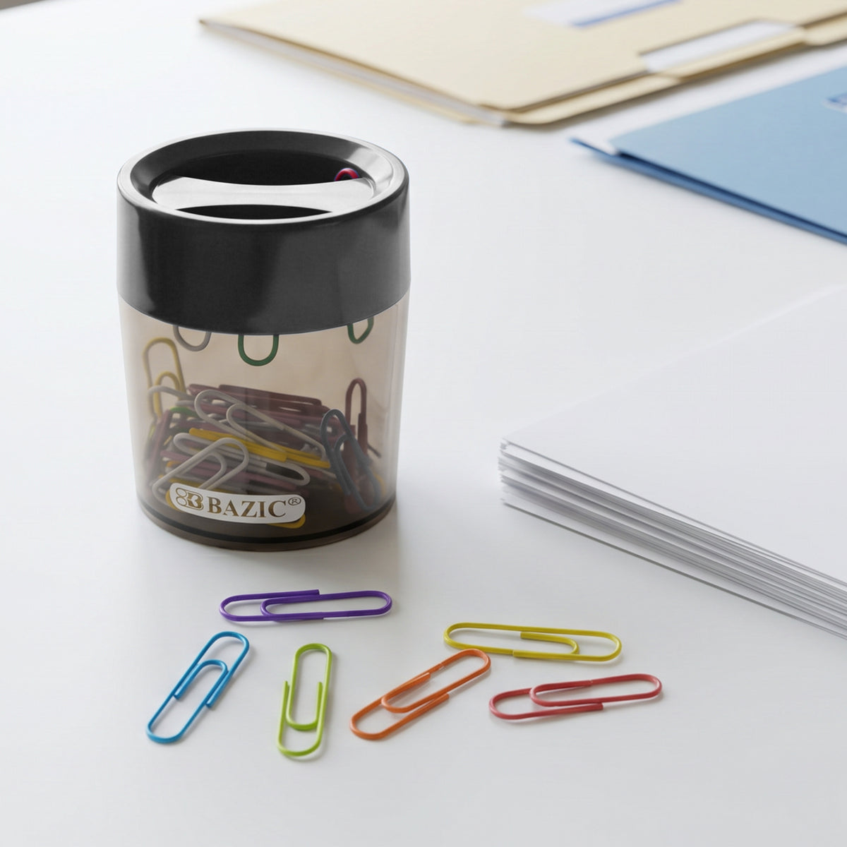 Clear holder with a black top on a desk, with six loose clips in purple, blue, green, orange, yellow and red.