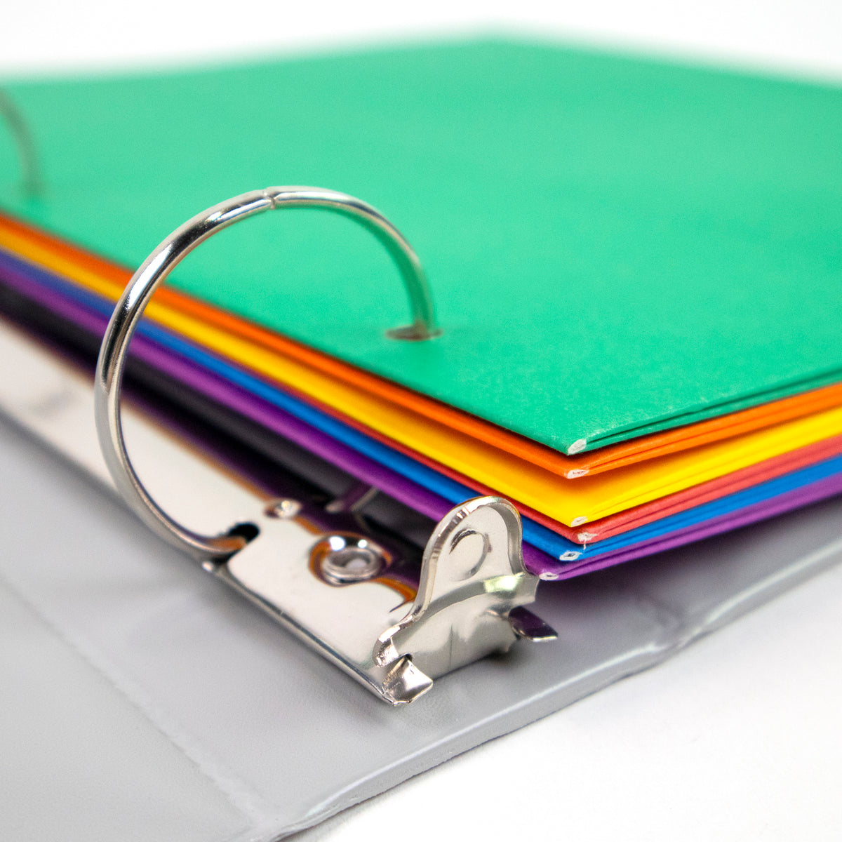 Close-up of colorful folders punched for binder storage, with green, orange, yellow, red, blue and purple edges.