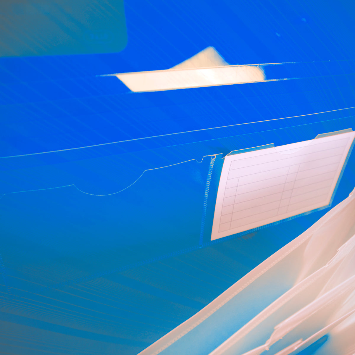 Close-up inside the blue folder shows clear card pockets, a blank lined label card and translucent expanding dividers.