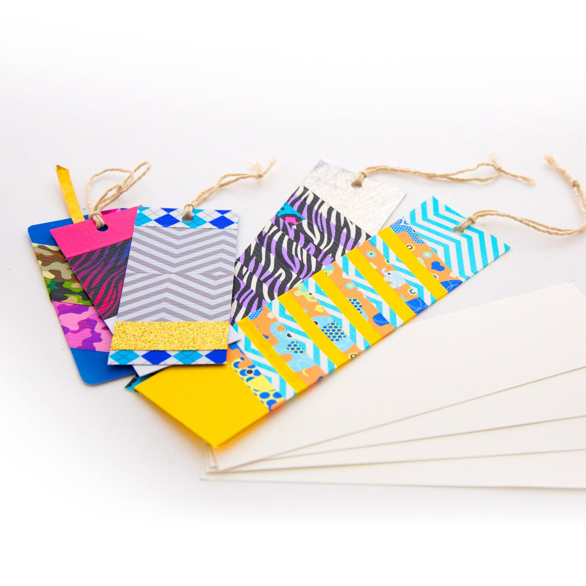Colorful patterned bookmarks with twine ties beside blank white poster board strips.