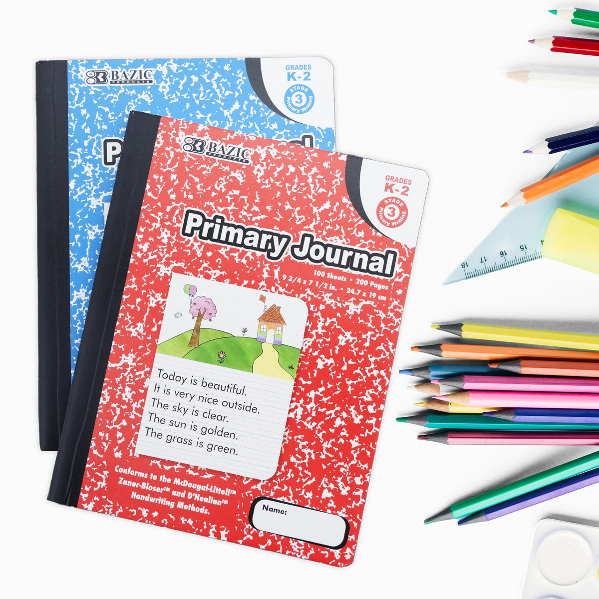 Red and blue marbled journals beside colored pencils; grades K–2, 100 sheets, 200 pages, 9¾ × 7½ inches.