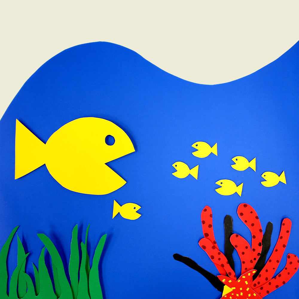 Underwater craft scene on blue poster board with yellow fish, green seaweed, red coral and a red-and-yellow starfish.