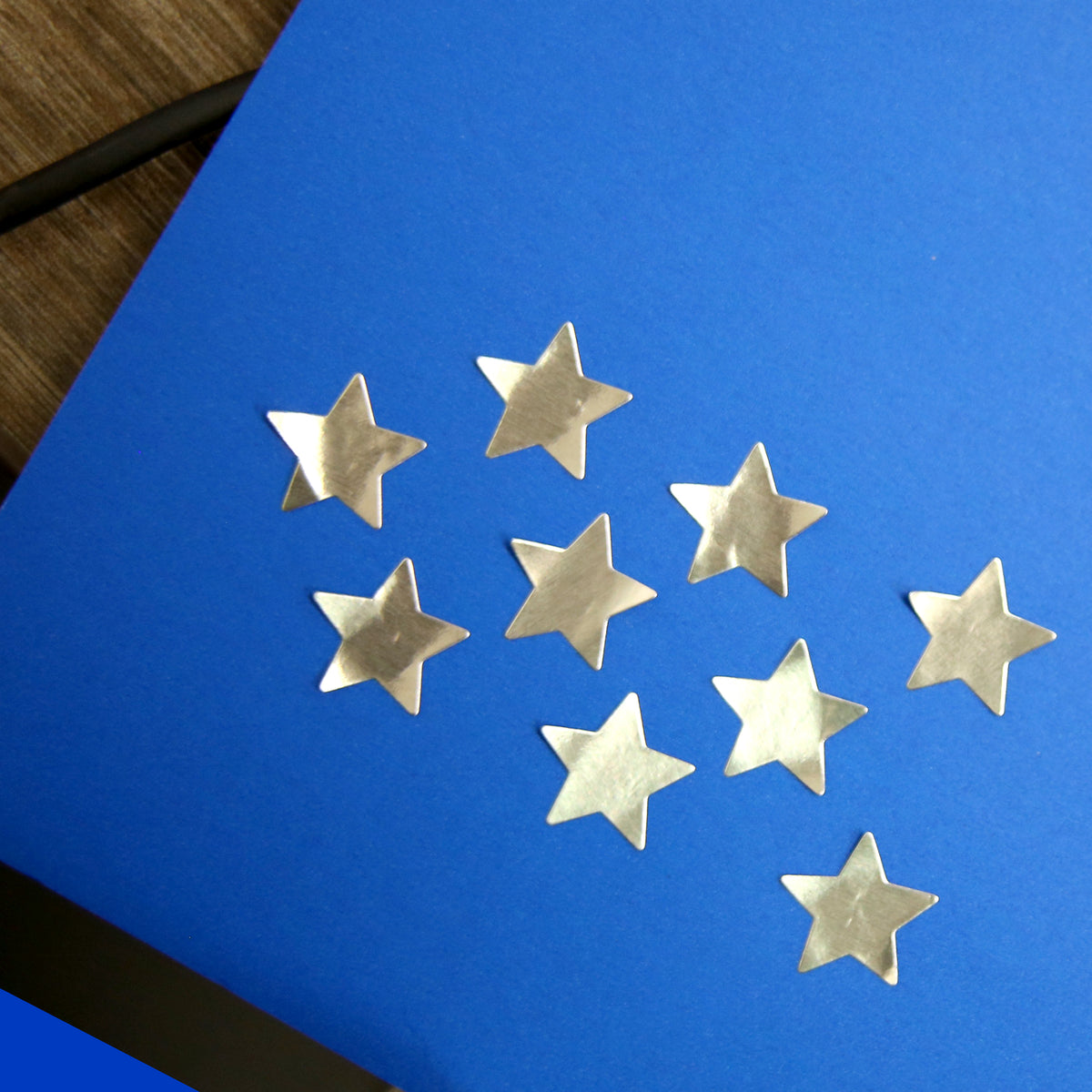 Blue poster board decorated with nine metallic gold stars on a wooden surface.