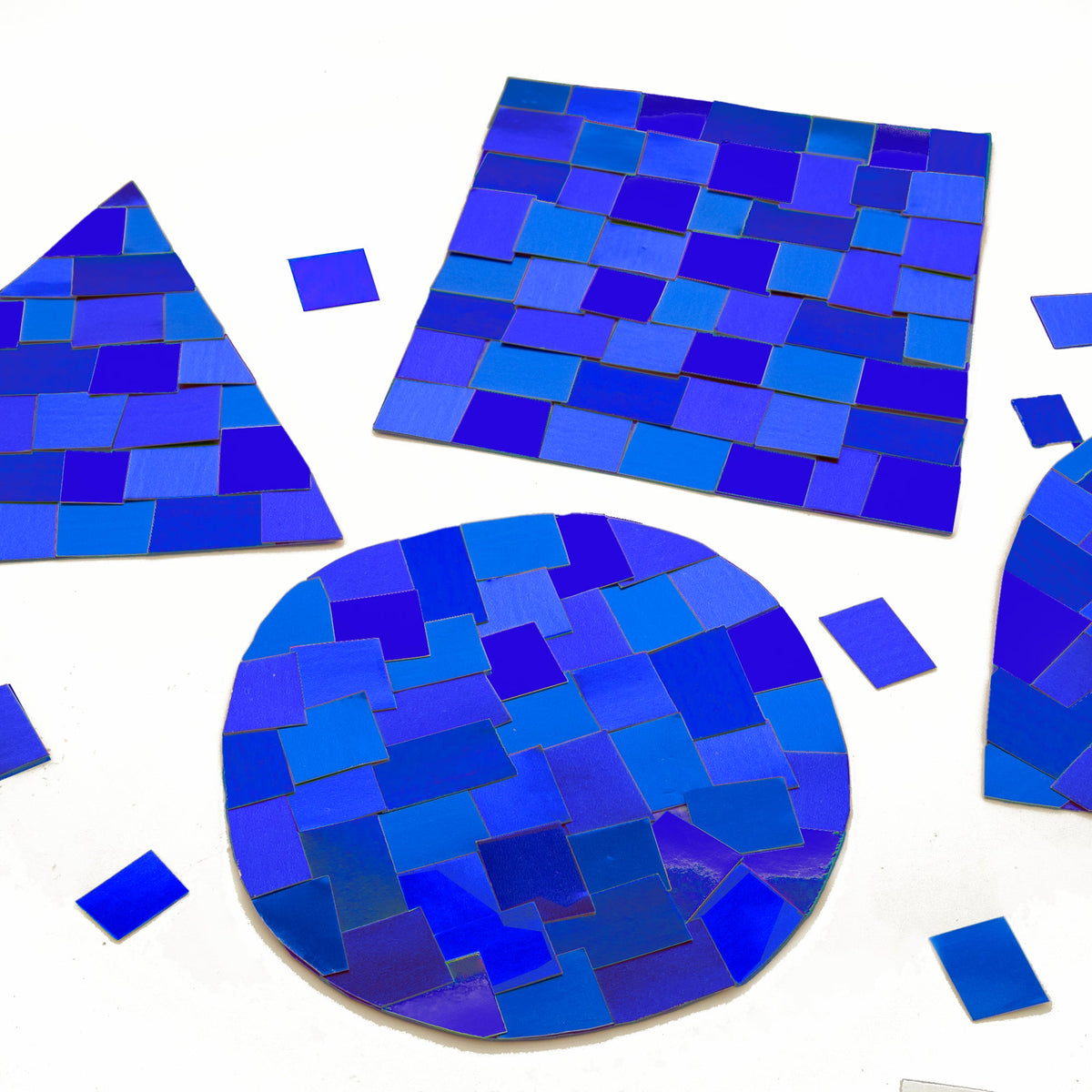 Metallic blue rectangles arranged as mosaics on circular, square and triangular shapes, with loose pieces nearby.
