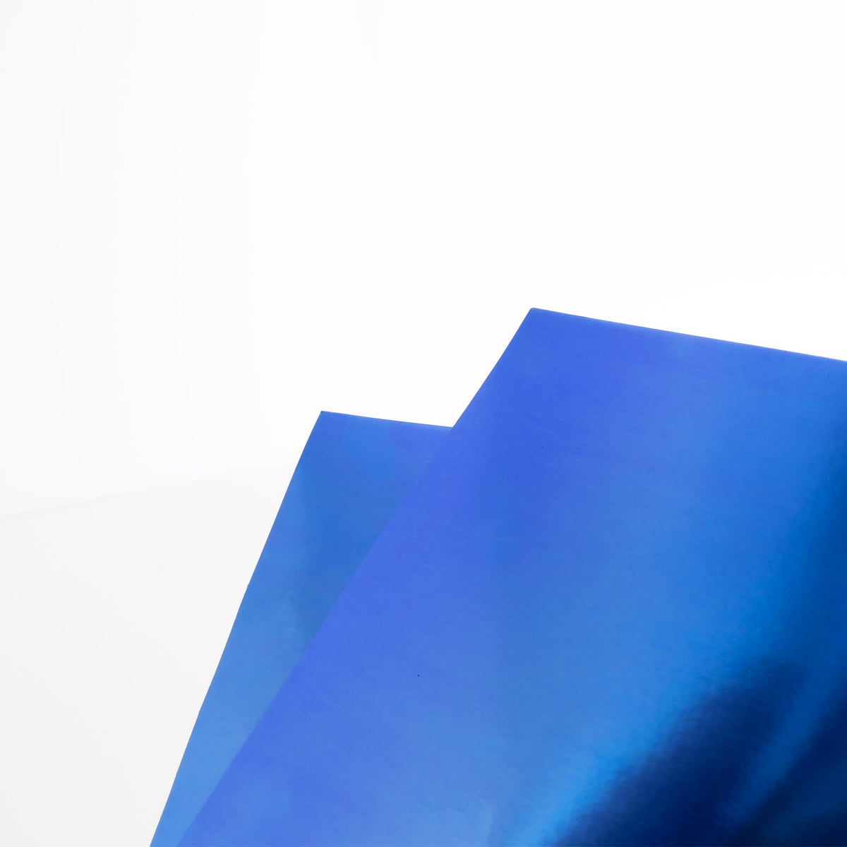 Close-up of two overlapping blue poster boards with a smooth, reflective metallic finish.
