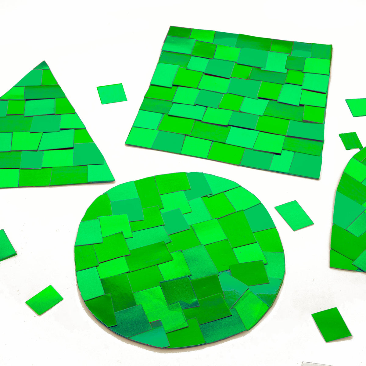 Metallic green rectangles form mosaic patterns on circle, square and triangle craft shapes, with loose pieces nearby.