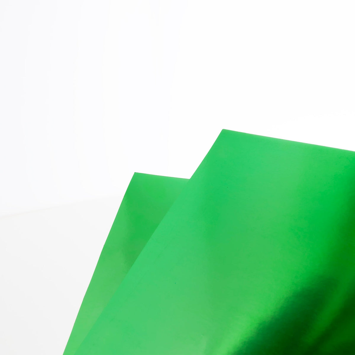 Close-up of two overlapping green poster boards with a reflective metallic finish.