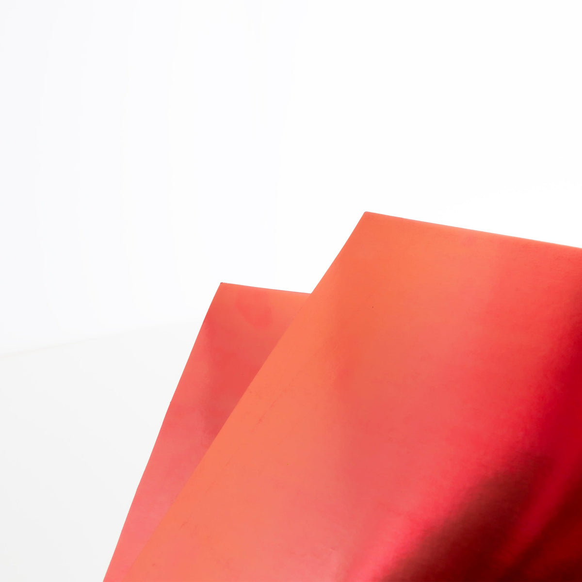 Close-up of two overlapping red poster boards showing their reflective metallic surfaces and straight edges.