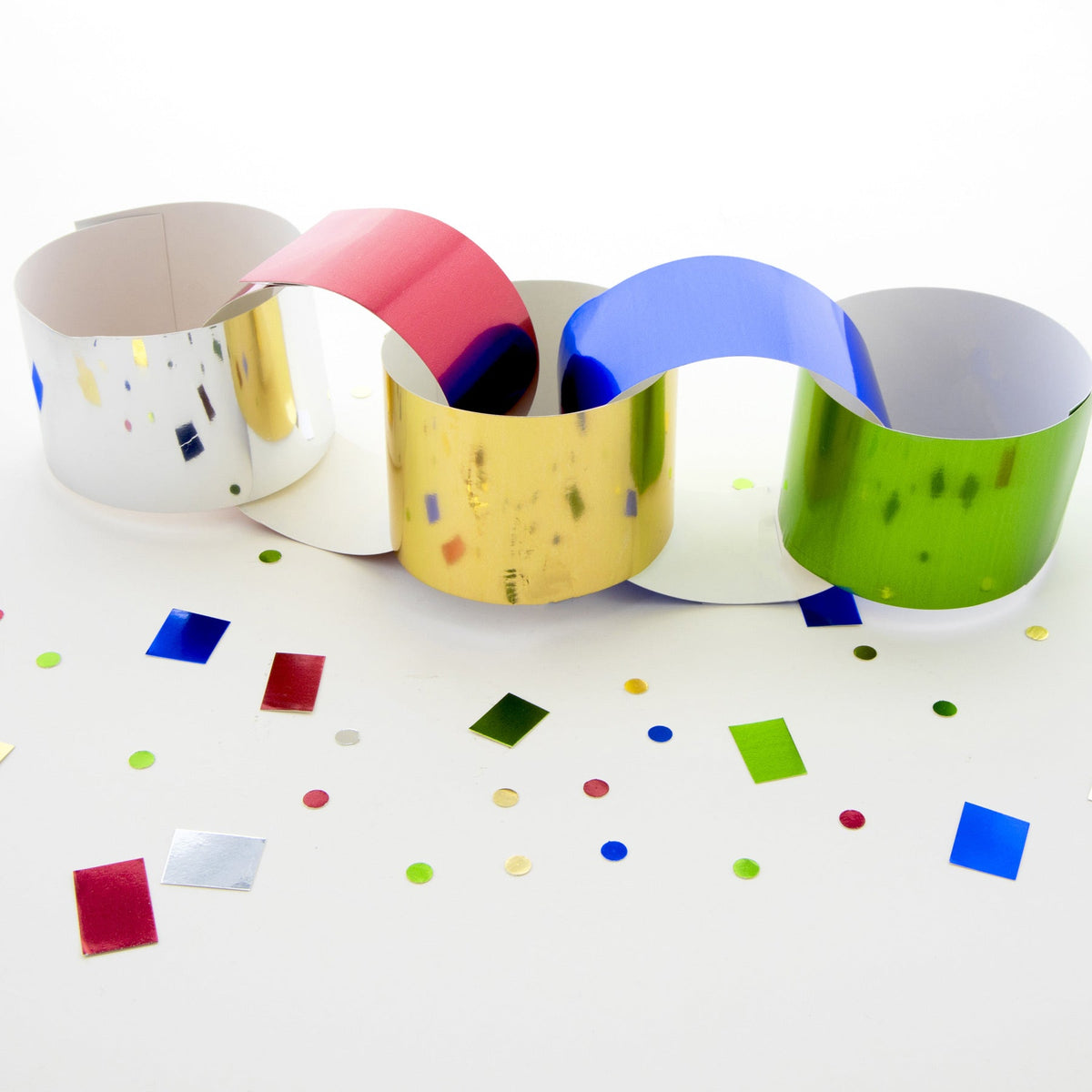 Metallic board strips form linked loops in gold, silver, red, blue and green, with small circle and square cutouts.