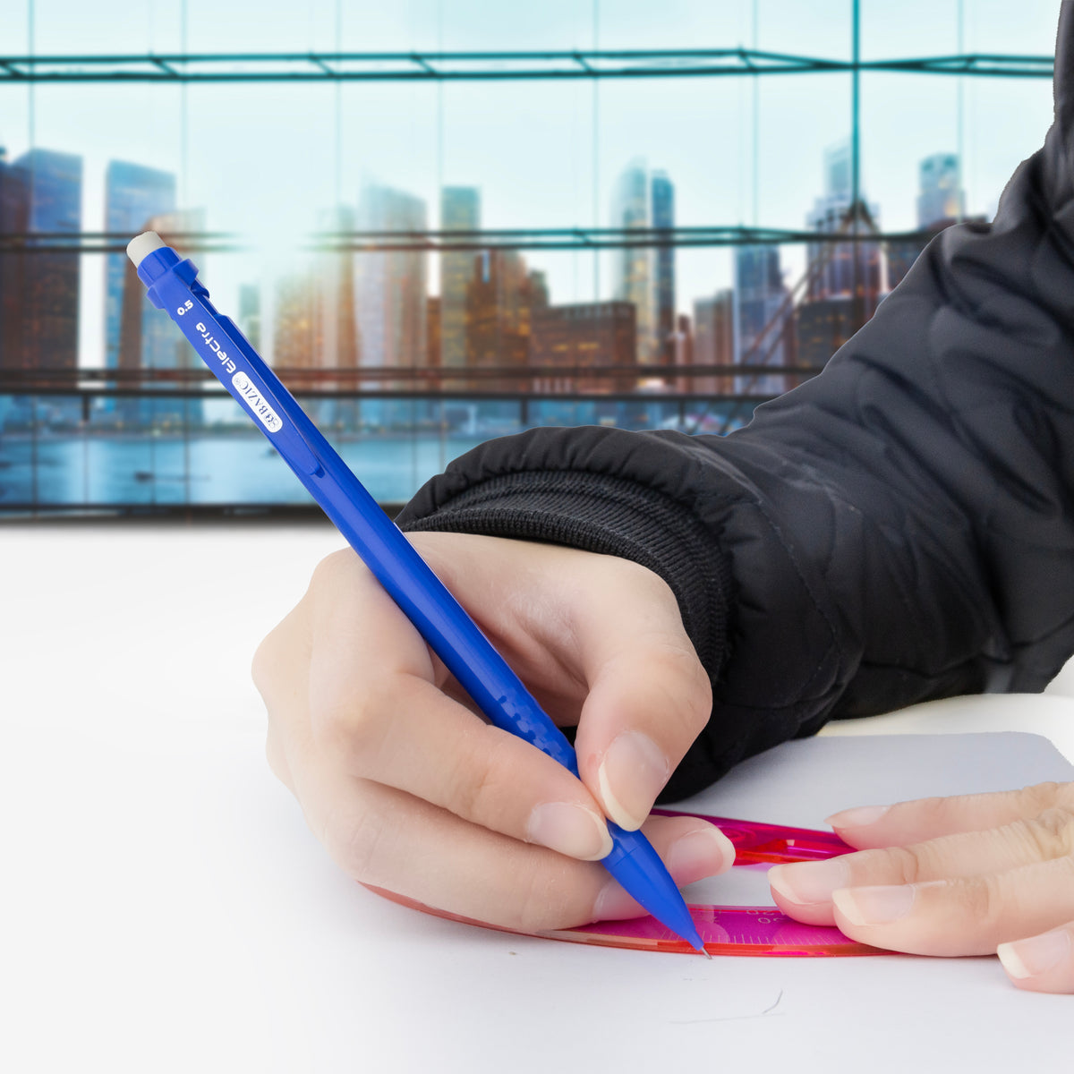 A person uses a blue mechanical pencil to draw along a pink ruler on white paper.